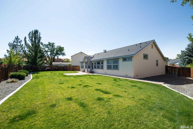 rear view of property with crawl space, a yard, a fenced backyard, and a patio