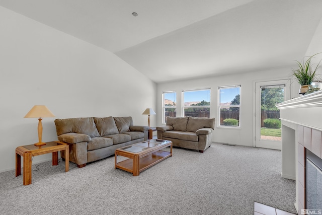 carpeted living area with lofted ceiling, a tiled fireplace, and visible vents