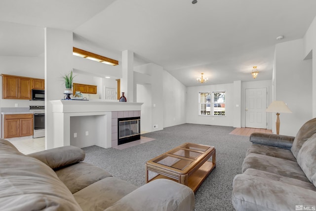 living room with light carpet, vaulted ceiling, and a tile fireplace