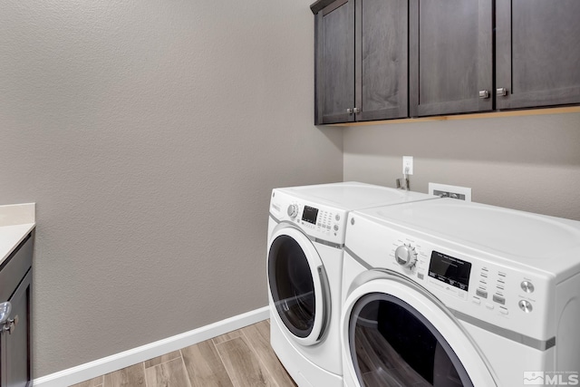 laundry area with cabinets, light wood-type flooring, and washing machine and dryer