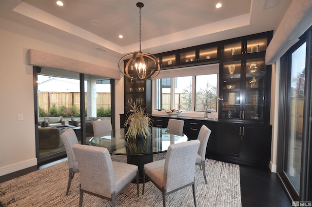 dining room featuring a chandelier, recessed lighting, wood finished floors, baseboards, and a raised ceiling