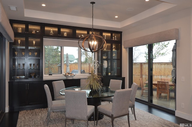 dining room with a tray ceiling, a healthy amount of sunlight, and a notable chandelier