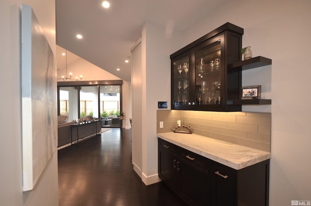 bar featuring recessed lighting, dark wood-type flooring, vaulted ceiling, decorative backsplash, and a bar