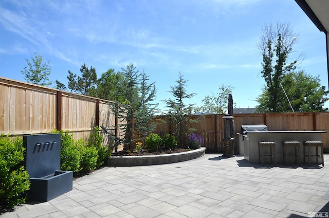 view of patio with a fenced backyard, outdoor dry bar, and grilling area