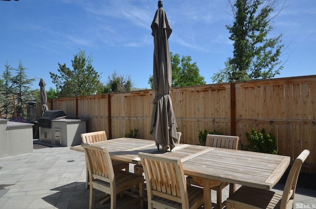 view of patio with outdoor dining area, a fenced backyard, and area for grilling