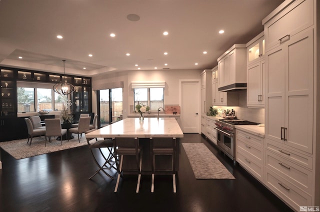 kitchen featuring range with two ovens, recessed lighting, dark wood-style flooring, and a kitchen island with sink