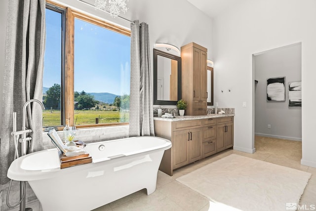 bathroom with tile patterned flooring, vanity, a mountain view, and a tub