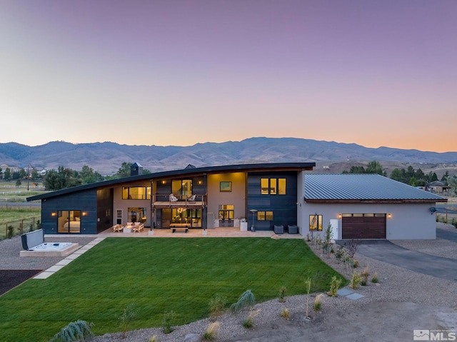 contemporary home with a mountain view, a yard, and a patio area