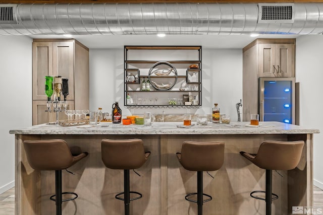 bar with light wood-type flooring and light stone counters