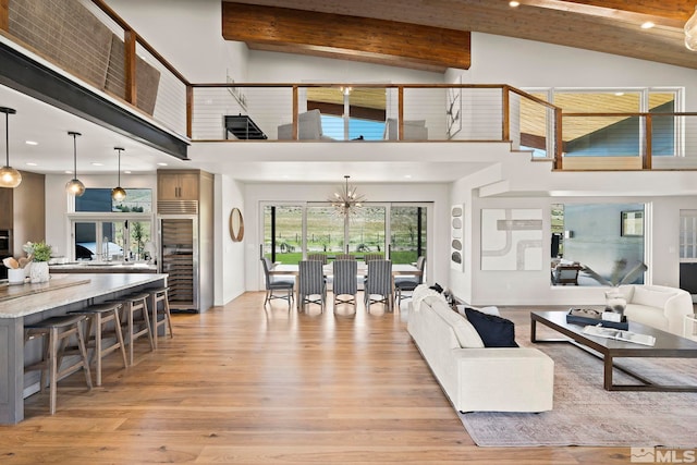 living room with high vaulted ceiling, light hardwood / wood-style flooring, a chandelier, and beamed ceiling