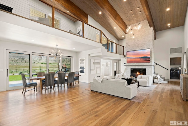 living room with high vaulted ceiling, light hardwood / wood-style floors, beamed ceiling, and a stone fireplace