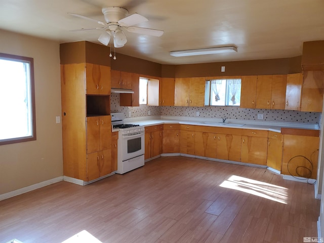 kitchen featuring a healthy amount of sunlight, ceiling fan, white gas range, and light hardwood / wood-style floors