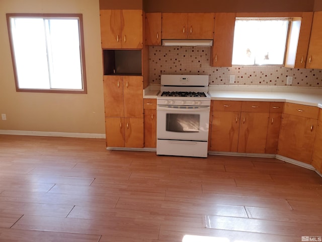 kitchen with light hardwood / wood-style floors, backsplash, and white gas stove