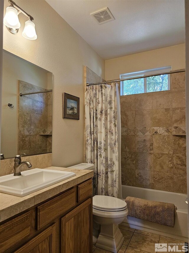 full bathroom with a textured ceiling, vanity, tile patterned flooring, toilet, and shower / bath combo with shower curtain