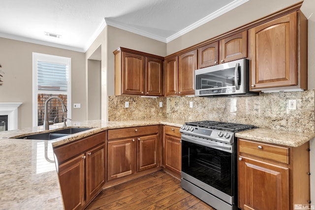 kitchen featuring dark hardwood / wood-style floors, crown molding, stainless steel appliances, sink, and decorative backsplash