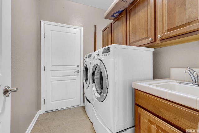 clothes washing area featuring light tile patterned floors, cabinets, and washing machine and clothes dryer