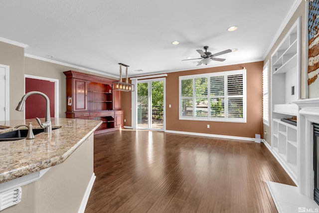 kitchen featuring decorative light fixtures, dark hardwood / wood-style floors, crown molding, and sink