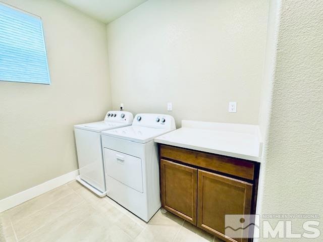 washroom with cabinets, washing machine and dryer, and light tile patterned floors