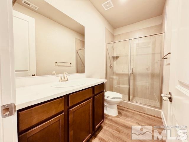 bathroom with a shower with door, vanity, toilet, and hardwood / wood-style floors