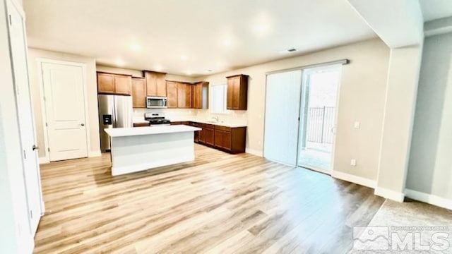 kitchen with appliances with stainless steel finishes, light hardwood / wood-style flooring, and a center island