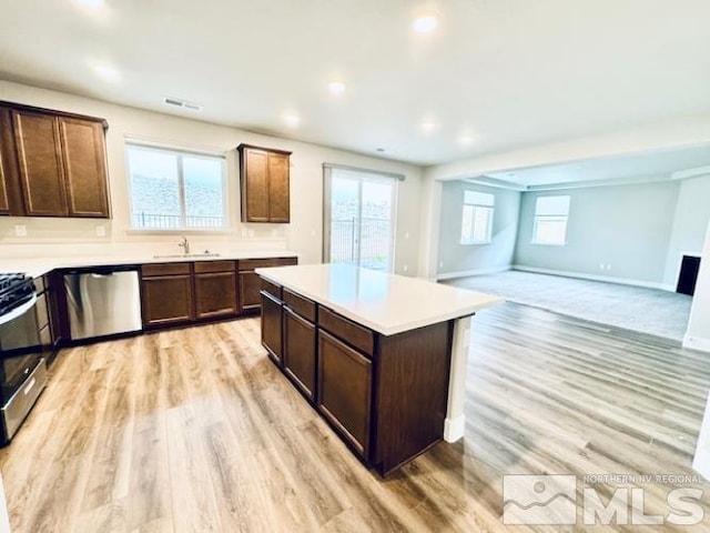 kitchen featuring a healthy amount of sunlight, a kitchen island, stainless steel appliances, and light hardwood / wood-style floors