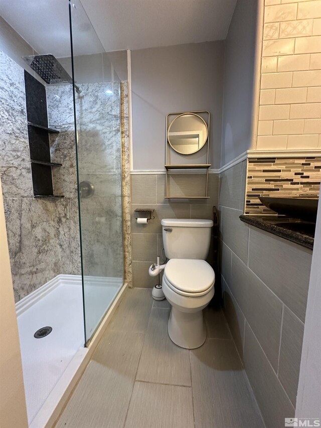 bathroom featuring tile walls, toilet, a tile shower, and tile patterned flooring