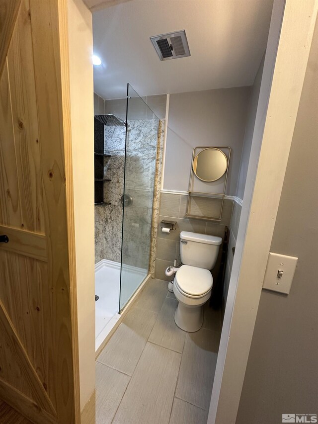 bathroom featuring toilet, walk in shower, and tile patterned flooring