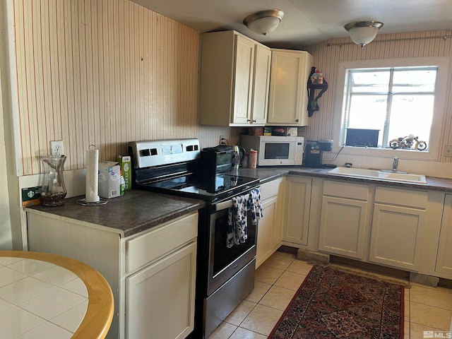 kitchen featuring light tile patterned floors, stainless steel range with electric cooktop, and sink