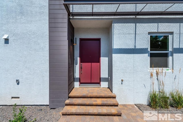 doorway to property featuring crawl space and stucco siding