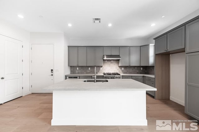 kitchen featuring a center island with sink, visible vents, gray cabinetry, under cabinet range hood, and a sink