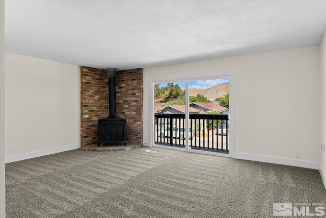 unfurnished living room featuring a wood stove, a textured ceiling, and carpet floors