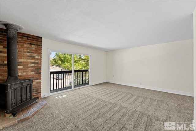 unfurnished living room with a textured ceiling, a wood stove, and carpet flooring