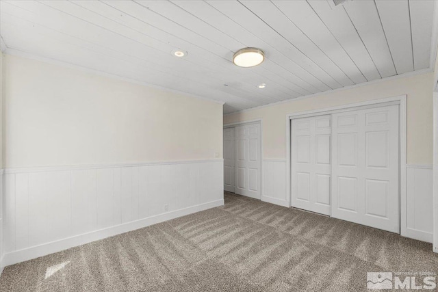 unfurnished bedroom with two closets, carpet flooring, and wood ceiling