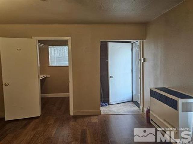 interior space with heating unit, a textured ceiling, baseboards, and wood finished floors