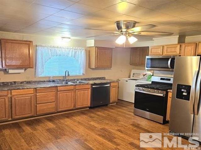 kitchen featuring washer / dryer, dark wood-style flooring, ceiling fan, a sink, and appliances with stainless steel finishes