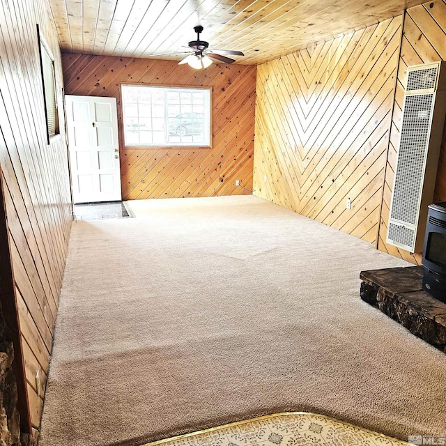 carpeted living room featuring a wood stove, wood ceiling, and wood walls