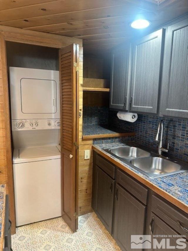 kitchen with decorative backsplash, wooden ceiling, stacked washer and dryer, and a sink