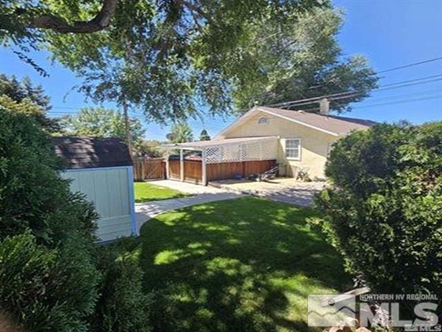 view of yard featuring a storage shed, an outdoor structure, and fence