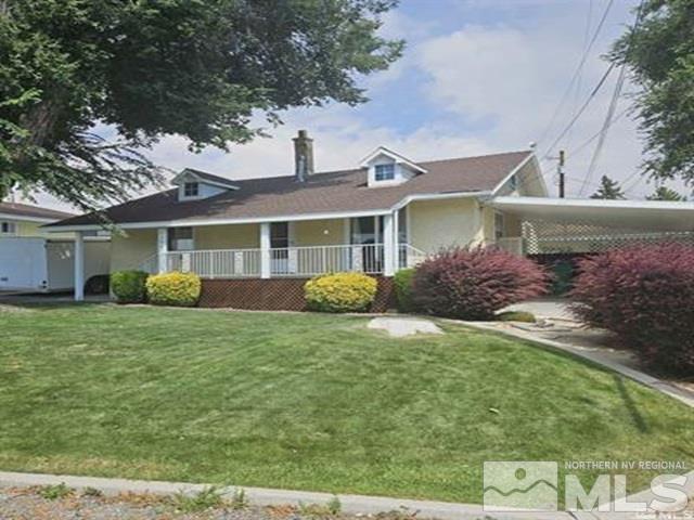 view of front of home with covered porch, a chimney, a front yard, and an attached carport
