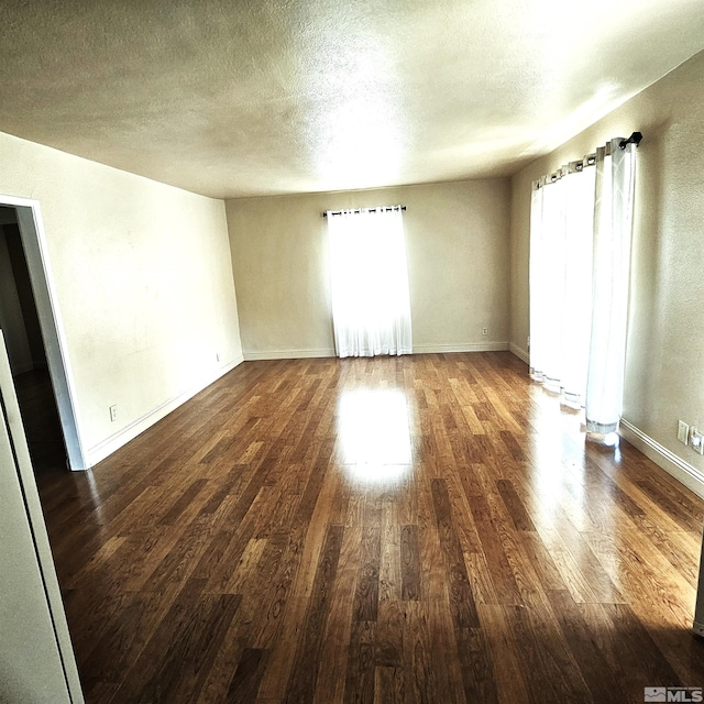 unfurnished room with wood finished floors, baseboards, and a textured ceiling