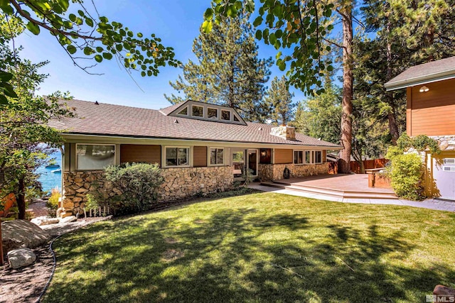 back of property with stone siding, fence, a lawn, and a patio