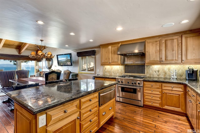 kitchen featuring a warming drawer, tasteful backsplash, stainless steel stove, dark wood-type flooring, and wall chimney range hood