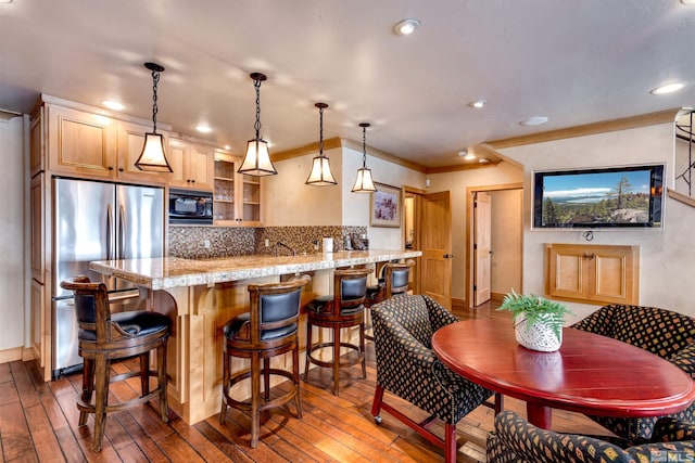 kitchen featuring freestanding refrigerator, black microwave, backsplash, and dark wood-style flooring