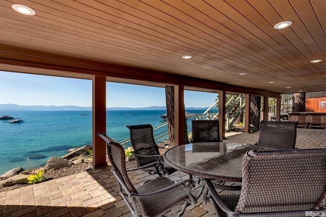 view of patio with stairs, outdoor dining area, and a water and mountain view