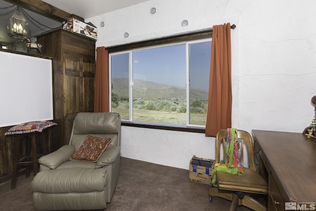 sitting room featuring a mountain view, unfinished concrete flooring, and a textured wall