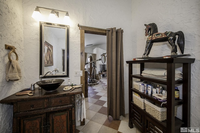 hall featuring light floors, a textured wall, and a sink