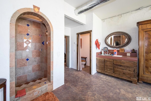 bathroom with vanity, toilet, and a tile shower