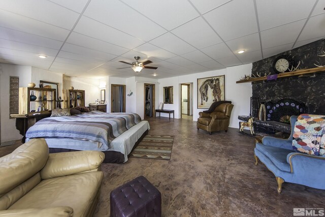 bedroom with a paneled ceiling, ceiling fan, and a large fireplace