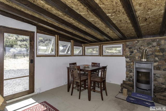 dining area with plenty of natural light, a wood stove, and vaulted ceiling