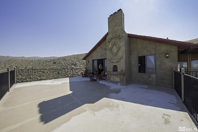 view of patio / terrace with an outdoor stone fireplace and fence